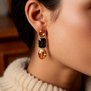 Detail of vintage gold earring with orange oval and black rectangular rhinestones