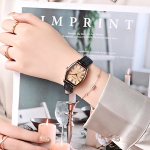 Montre tonneau élégante en or rose avec chiffres romains et bracelet en cuir noir au poignet