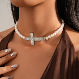 Detailed close-up of a Baroque pearl necklace featuring a diamond-studded horizontal cross
