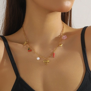 Gold stainless steel necklace with cherry, bow, and heart charms worn by a model