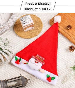 Close-up of red plush Christmas hat with Santa Claus patch among festive decorations