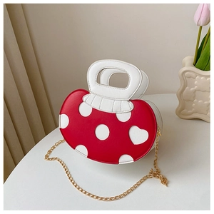 Detailed close-up of a red and white polka dot heart pattern handbag with a gold chain strap