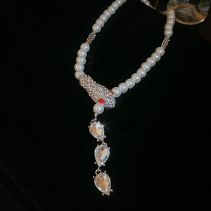 Detail of pearl necklace featuring a diamond-set snake head with teardrop crystals