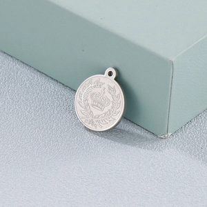Silver round steel pendant featuring embossed crown and laurel wreath on a gift box