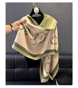 Detail of green and beige cashmere scarf featuring classic chain and horsebit patterns