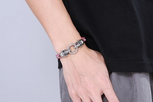 Close-up of a silver stainless steel skull bracelet with red accents on a male wrist
