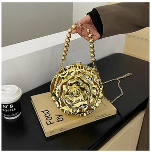 Detail of golden rose evening bag with beaded handle and metallic 3D floral texture
