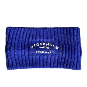 Detailansicht des kornblumenblauen Strickstirnbandes mit weißem Stockholm-Schriftzug und Rippmuster