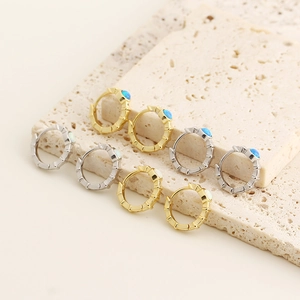 Detail of s925 silver opal huggie earrings in gold and silver finish on stone