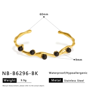 Macro detail of gold stainless steel bangle with lava texture and black beads showing dimensions