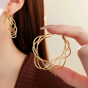Detailed view of large gold hollow spiral twisted hoop earrings with silver needle posts