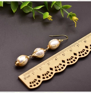 Detail of 925 silver ear hook with three natural freshwater pearls wrapped in gold wire