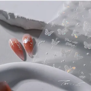 Macro shot of 3D aurora white butterfly nail art stickers with laser star and moon patterns