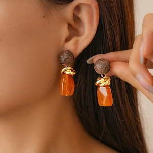 Detail of vintage resin hoop earring with wood top and golden metal knot pendant
