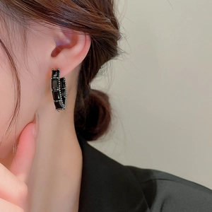 Gros plan détaillé de boucles d'oreilles en C avec zircons noirs sur un mannequin