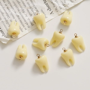 Flat lay view of eight realistic resin tooth charms on beige background and newspaper