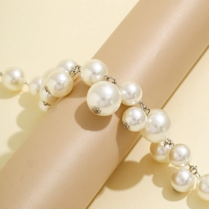 Detail of faux pearl necklace with silver flower clasps on a cylindrical jewelry display