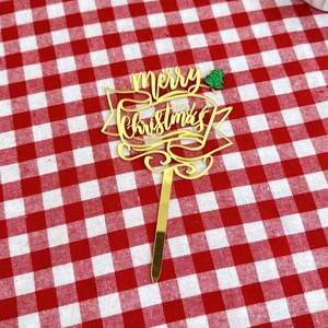 Detail of golden acrylic Merry Christmas cake topper with a green glitter tree