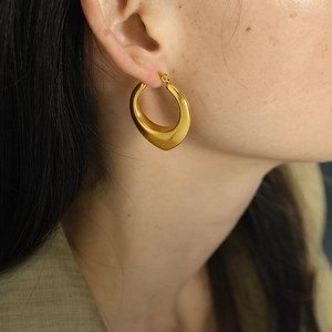 Polished gold teardrop hoop earrings in chunky U-shape style worn by a female model