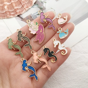 Close-up of colorful enamel mermaid and seahorse pendants with gold metal base