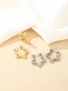 Macro detail of gold and silver star earrings with a shimmering frosted textured finish