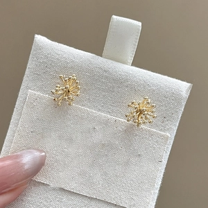 Macro detail of 18k gold plated firework stud earrings with zircons and pearls