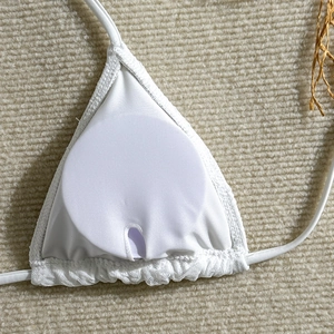 Close-up of white bikini top showing lace trim and removable bra pad insert design