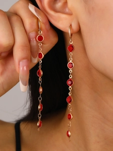 Gros plan de longues boucles d'oreilles dorées avec cristaux rouges sur un modèle