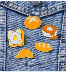 Détail de cinq broches en émail en forme de pain sur la poche d'une veste en jean