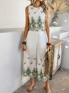 Outdoor shot of a woman in a white two-piece set with green embroidery and wide-leg pants
