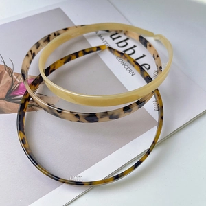 Detailed view of 3-piece non-slip acetate headbands in tortoise and cream on a magazine