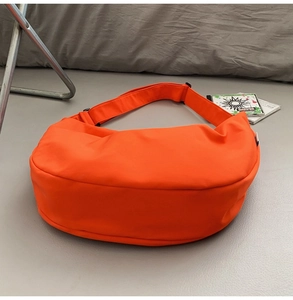 Detail of a bright orange oxford fabric crescent crossbody bag with adjustable strap