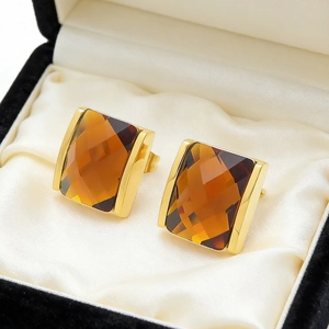 Macro shot of square amber glass earrings set in 18K gold base on satin lining