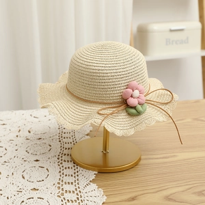 Detailed straw sun hat for kids featuring wavy petal brim and pink fabric flower ornament