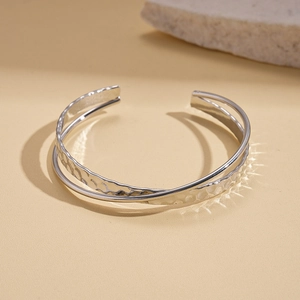 Detail of silver double-layered crisscross open bangle with hammered water ripple texture