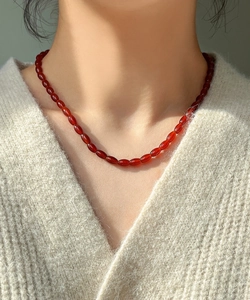 Detail of oval red agate beads necklace on model with soft natural light shadows