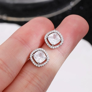 Elegantes pendientes cuadrados halo de plata con circonitas mostrados en mano