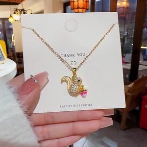 Close-up of squirrel pendant with cubic zirconia and gradient acorn on golden chain