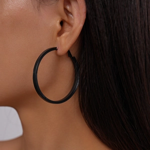 Close-up of matte black geometric round hoop earrings on model for minimalist style