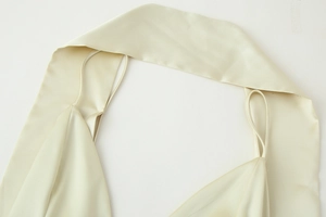 Close-up of champagne gold satin dress showing halter neck strap and fabric texture