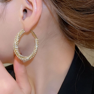 Close-up of sparkling large gold twisted hoop earrings with micro-pave diamond crystals