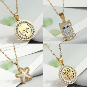 Detail view of four gold-plated pendants featuring skull, owl, starfish, and tree of life