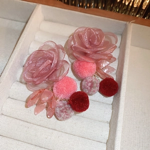 Detail view of pink lace flower earrings with soft pom-poms and resin leaf charms