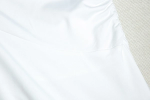 Close-up of white dress fabric showing high-quality twill texture and neat stitching details