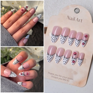 Macro shot of French pink press-on nails with black polka dots and 3D bow details