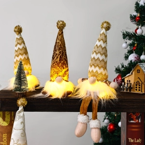 Close-up of three glowing Christmas gnomes with golden knit hats and warm LED lights