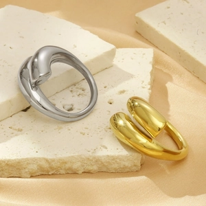Close-up of minimalist liquid metal rings in gold and silver on textured travertine stone