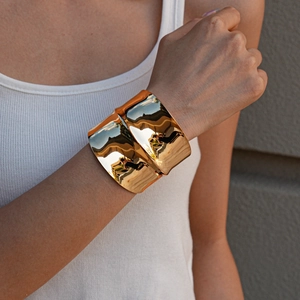 Close-up of wavy gold-plated cuff bracelet with high-polish mirror finish on a female model