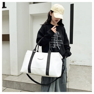 Detail view of large white travel bag with black adjustable shoulder strap and handles