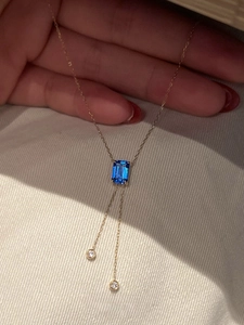 Détail d'un collier avec pendentif carré en pierre bleue et chaîne dorée élégante